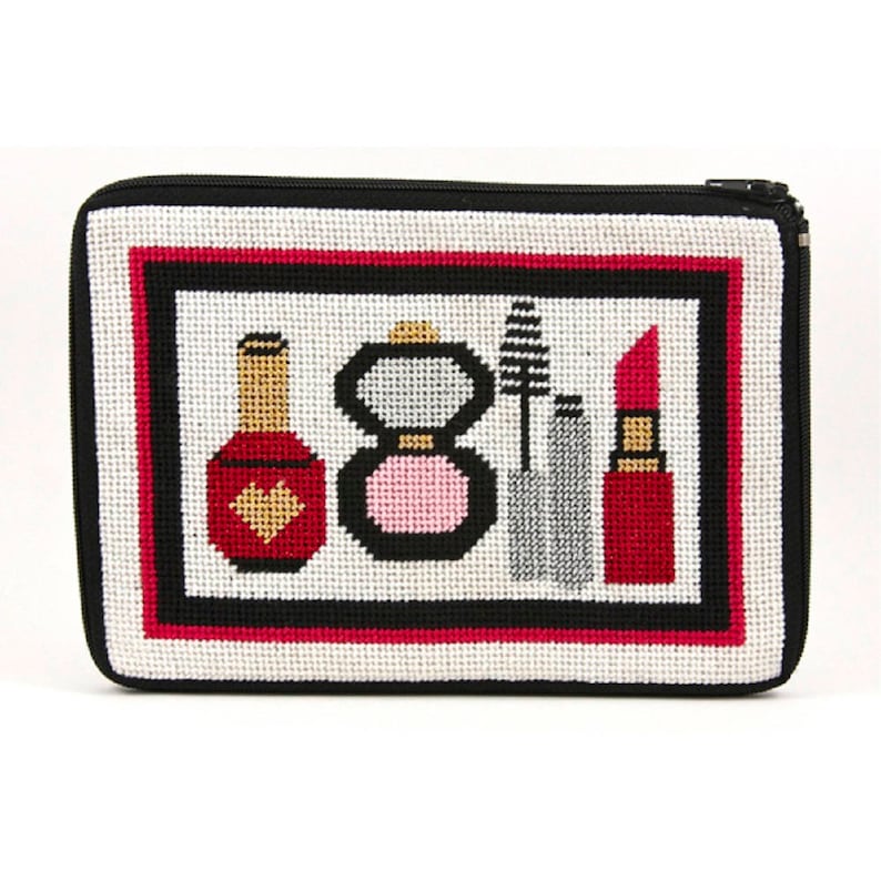 May include: A white canvas zippered pouch with a black zipper and a black border. The pouch has a colorful embroidered design of makeup items, including a red nail polish bottle, a pink blush compact, a black mascara wand, a silver eyeliner pencil, and a red lipstick.