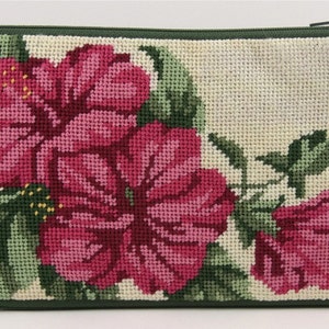 May include: A green zippered pouch with a needlepoint design of pink hibiscus flowers on a cream background.