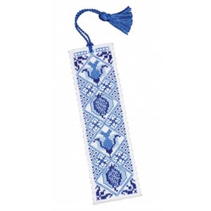 May include: A white bookmark with a blue and white embroidered design of stylized flowers and geometric patterns. The bookmark has a blue tassel.