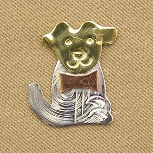May include: A silver and gold metal dog figurine with a copper bow tie. The dog is sitting with its head tilted and its tail curled.