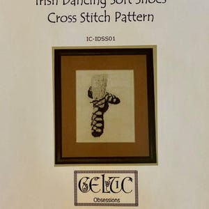 May include: A cross stitch pattern titled Irish Dancing Soft Shoes Cross Stitch Pattern IC-IDSS01. The image shows a framed cross stitch of a dark shoe on a light background. The text Celtic Obsessions and Finished Dimensions: 2.9 inches x 6.2 inches 16 Count are visible.