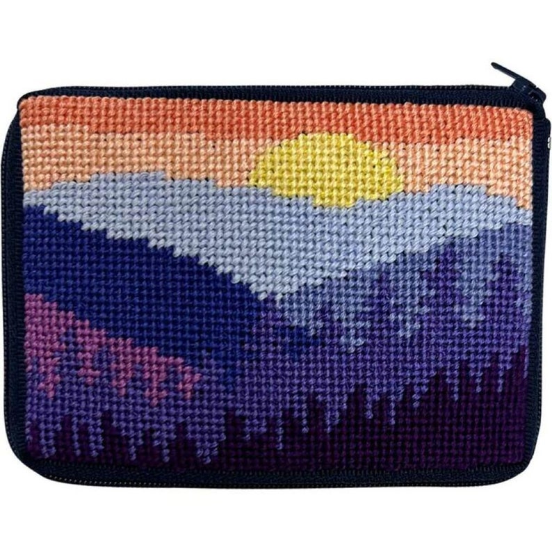 May include: A small zippered pouch with a needlepoint design of a sunset over mountains. The mountains are shades of purple, blue, and pink, with a yellow sun setting behind them. The pouch is lined with black fabric.