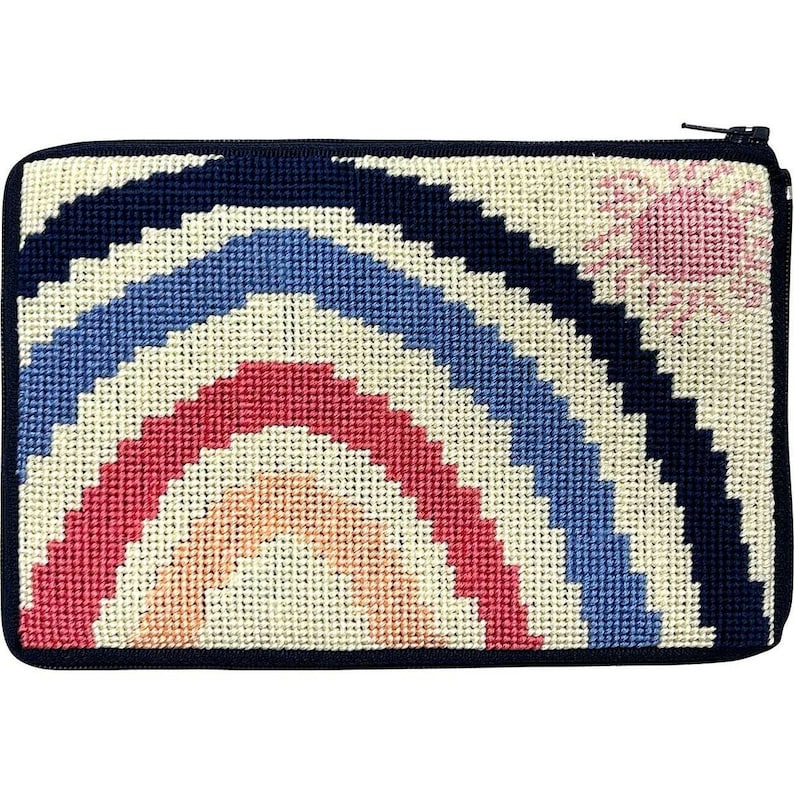 Op de afbeelding: Een rechthoekig, met de hand gestikt etui met een marineblauwe ritssluiting en rand. Het ontwerp toont een regenboogboog in tinten rood, blauw en cr&egrave;me, met een roze zon in de rechterbovenhoek. Het etui is waarschijnlijk gemaakt van canvas of een vergelijkbaar materiaal.