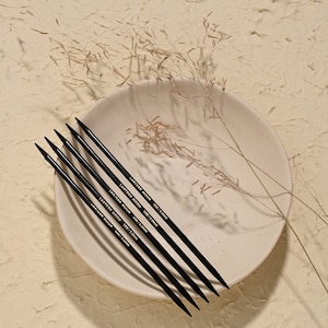 May include: Five black knitting needles with gold lettering on a white plate. The lettering reads "LANTERN MOON" and "US8/5.0mm".