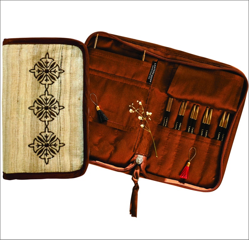 Puede incluir: Una funda de cuero marr&oacute;n con cierre de cremallera, que contiene un juego de agujas de tejer. La funda tiene un peque&ntilde;o bolsillo en la parte delantera y un borla en el tirador de la cremallera. Las agujas est&aacute;n dispuestas en filas y est&aacute;n etiquetadas con "LATHERINGTON NEEDLE CRAFTS".