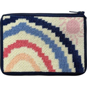 May include: A small zippered pouch with a colorful rainbow design. The pouch is made of needlepoint fabric and has a navy blue border.