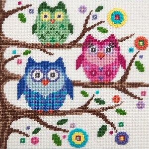 Pode incluir: Tr&ecirc;s corujas coloridas empoleiradas nos galhos de uma &aacute;rvore com folhas verdes e flores. As corujas s&atilde;o verde, rosa e azul com olhos brancos e pupilas pretas.