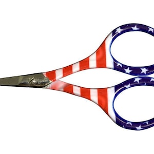 May include: A pair of small scissors with a red, white, and blue American flag design. The handles are made of plastic and the blades are made of metal.