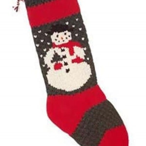 May include: A red and gray knitted Christmas stocking with a snowman design. The snowman is wearing a red scarf and hat.