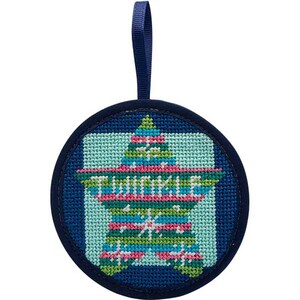 May include: A round, navy blue Christmas ornament with a stitched star design. The star is light blue with green, pink, and blue stripes and the word "TWINKLE" stitched across it. A navy blue ribbon is attached for hanging.
