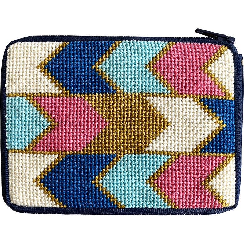 May include: A needlepoint zippered pouch with a geometric pattern of white, blue, pink, and gold arrows.