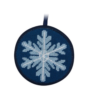 May include: A round, navy blue Christmas ornament with a light blue and white snowflake design. The snowflake is created with cross-stitch embroidery. A dark blue ribbon is attached for hanging.