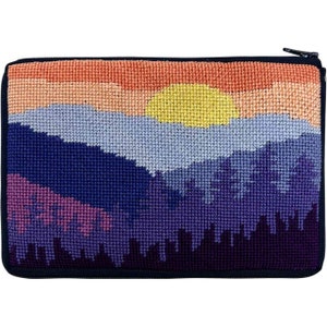 Op de afbeelding: Een rechthoekig etui met ritssluiting, versierd met een handgestikt landschap. Het ontwerp toont een zonsondergang met een gele zon en bergen in tinten paars, blauw en roze. Het etui heeft een zwarte ritssluiting en afwerking.
