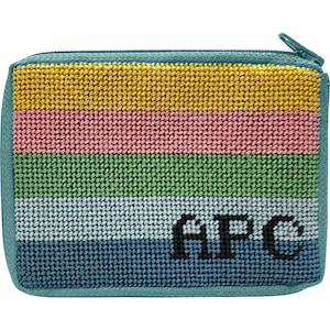 May include: A small, teal blue zippered pouch with a striped pattern in yellow, pink, green, light blue, and dark blue. The pouch has the letters "APC" embroidered in black on the front.