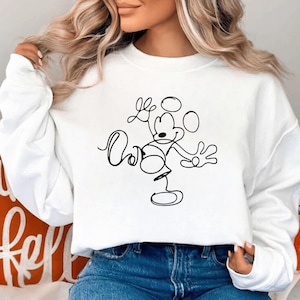 May include: White sweatshirt featuring a black line drawing of Mickey Mouse. The design includes the character's iconic ears, face, and body in a minimalist style. The sweatshirt is a casual, comfortable garment.
