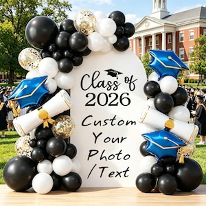 Op de afbeelding: Een achtergrond voor een afstudeerfotohokje met een witte boog, zwarte, witte en gouden ballonnen en blauwe afstudeerhoedballonnen. De tekst luidt "Class of 2026 Custom Your Photo / Text."