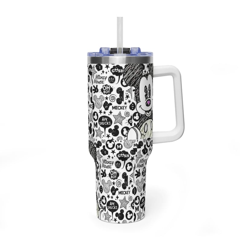 May include: A stainless steel tumbler with a white handle, a clear lid, and a straw. The exterior features a black and white sketch-style pattern of Mickey Mouse faces, stars, swirls, and speech bubbles with text including Mickey Mouse and Oh Boy.