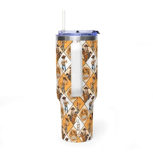 Puede incluir: Un vaso de acero inoxidable con asa, tapa transparente y pajita. El exterior presenta un patr&oacute;n de rombos en naranja y blanco, decorado con ilustraciones de Sheriff Woody y el texto Sheriff Woody dentro de una insignia de estrella.