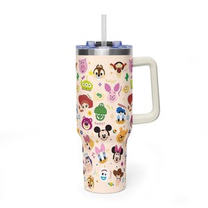 Puede incluir: Un vaso de acero inoxidable de color beige claro con asa, tapa transparente y pajita. El exterior presenta un patr&oacute;n repetitivo de caras de personajes de dibujos animados coloridos, incluyendo Mickey Mouse, Minnie Mouse, Donald Duck y varios personajes de Pixar.