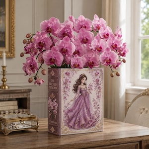 Puede incluir: Un florero rectangular con forma de libro titulado The Orchid Princess, que presenta la ilustración de una mujer con un vestido morado. El florero está lleno de numerosas orquídeas de color rosa vibrante con centros magenta oscuro.
