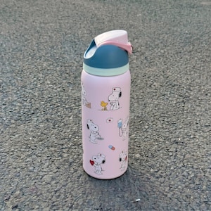 K&ouml;nnte beinhalten: Eine rosa isolierte Wasserflasche mit Snoopy in Krankenschwester-Uniform und medizinischen Illustrationen. Die Flasche hat einen blau-wei&szlig;en Deckel mit rosa Verschluss. Zum K&uuml;hlen von Getr&auml;nken.