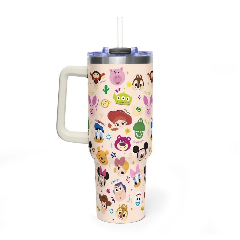 Puede incluir: Un vaso alto de acero inoxidable en color beige claro con asa y pajita transparente. El exterior presenta un patr&oacute;n repetitivo de varios rostros de personajes de dibujos animados, peque&ntilde;as estrellas y las palabras HAPPY, LOVE y SWEET.