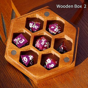 May include: A wooden hexagonal dice box with six compartments, each holding a purple die with white floral accents. The dice have white numbers. The box is labeled "Wooden Box 2".