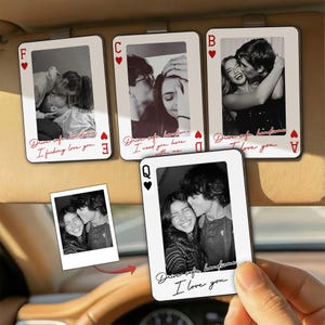 May include: A set of playing card-shaped car sun visors with black and white photos of couples. Each card has a red suit symbol and text in cursive. One card is held by a hand. The text includes "Drive safe handsome" and "I love you."
