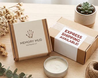 May include: A Memory Mud keepsake kit in a brown cardboard box with a white label featuring a handprint graphic and the text Memory Mud Keepsake Kit. Next to it is a second box with an Express Shipping Available label and a small metal tin of clay.
