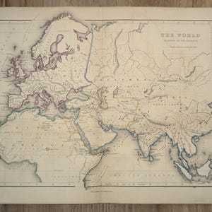 May include: Antique world map with detailed geographical features, including continents, oceans, and country borders. The map is printed on aged paper, with the title "THE WORLD" at the top. The map is framed by a black border.