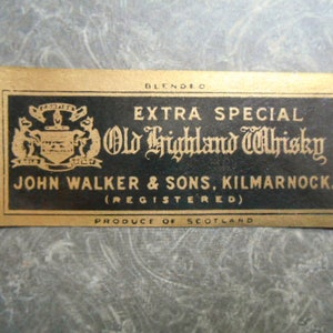 K&ouml;nnte beinhalten: Ein goldenes Etikett mit schwarzem Text, der "Blended Extra Special Old Highland Whisky John Walker & Sons, Kilmarnock. (Registered) Produce of Scotland" lautet. Das Etikett zeigt ein Wappen mit einem Schild und zwei L&ouml;wen.