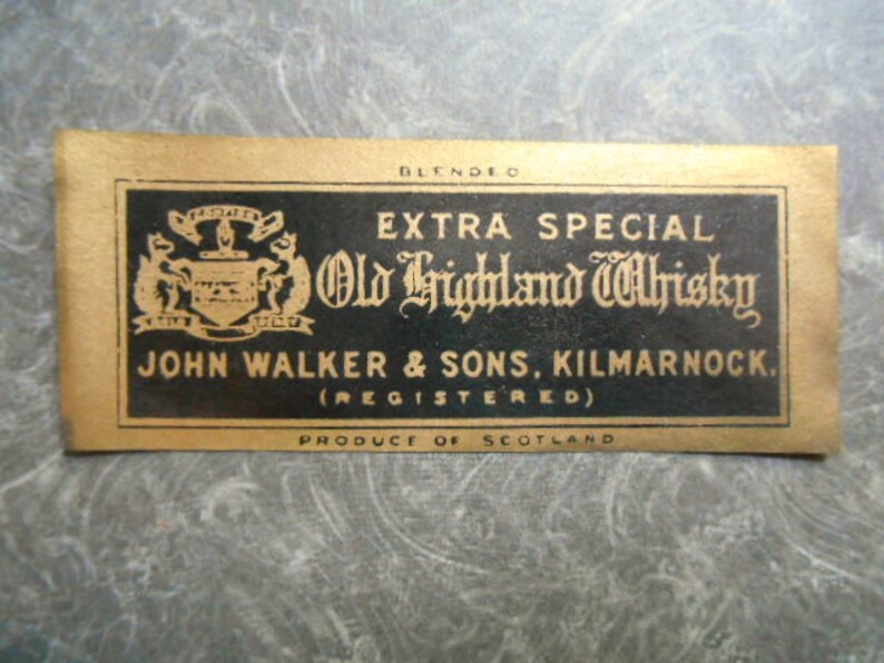 K&ouml;nnte beinhalten: Ein goldenes Etikett mit schwarzem Text, der "Blended Extra Special Old Highland Whisky John Walker & Sons, Kilmarnock. (Registered) Produce of Scotland" lautet. Das Etikett zeigt ein Wappen mit einem Schild und zwei L&ouml;wen.