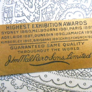 May include: A gold label with black text that reads "Highest Exhibition Awards" and lists cities and years. The text continues with "Guaranteed Same Quality Throughout the World" and "J.M. Hall & Sons, Limited".