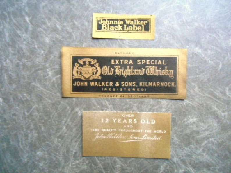 K&ouml;nnte beinhalten: Drei Vintage-Etiketten f&uuml;r Johnnie Walker Black Label Scotch Whisky. Das obere Etikett lautet "Johnnie Walker Black Label". Das mittlere Etikett lautet "Extra Special Old Highland Whisky John Walker & Sons, Kilmarnock (Registered) Produce of Scotland". Das untere Etikett lautet "Over 12 Years Old and Same Quality Throughout the World John Walker & Sons Limited".