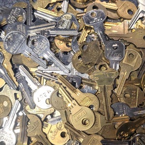 May include: A large pile of assorted keys, mostly brass and silver, with some having numbers and letters on them.