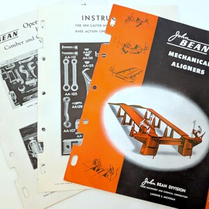 May include: A stack of vintage John Bean manuals. The cover of the main manual is black and orange, with the text "MECHANICAL ALIGNERS." Other manuals show diagrams and instructions for automotive repair.