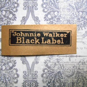 May include: A gold label with black text that reads "Johnnie Walker Black Label".