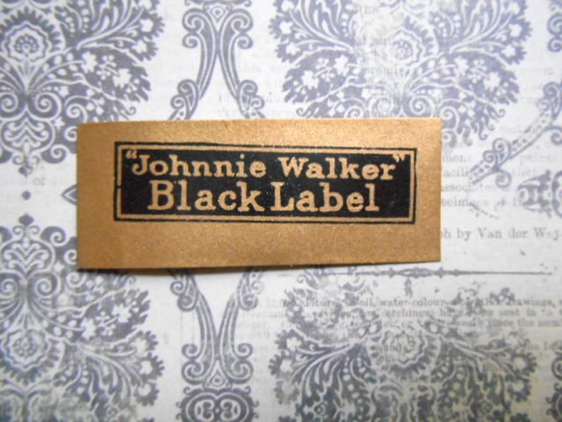 May include: A gold label with black text that reads "Johnnie Walker Black Label".