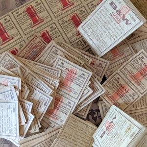 May include: A pile of vintage coupons for B&W cigarettes. The coupons are printed on paper with a red and white design. The text on the coupons reads "One Coupon" and "B&W Coupons".