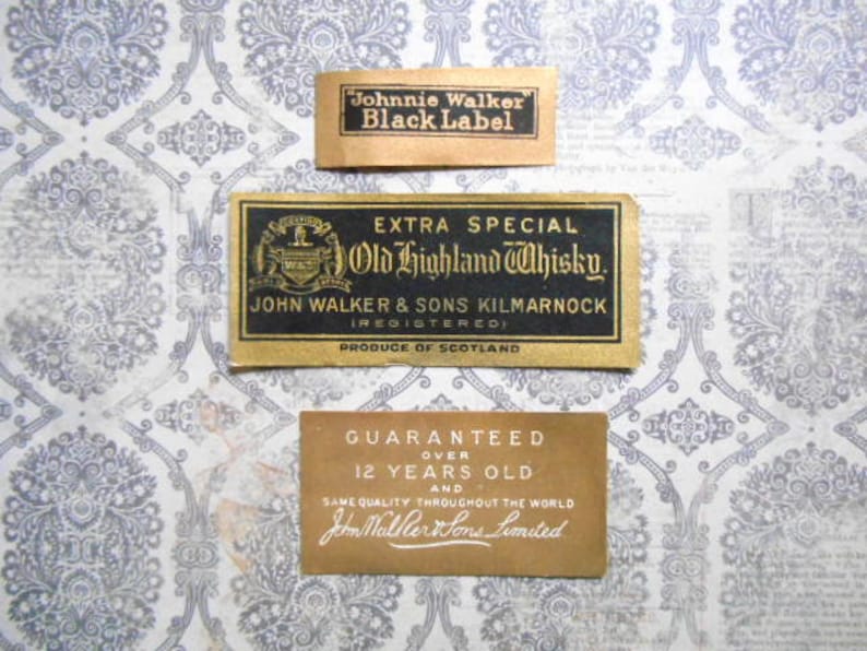 May include: Three vintage labels for Johnnie Walker Black Label Scotch Whisky. The labels are gold and black with white text. The top label reads "Johnnie Walker Black Label". The middle label reads "Extra Special Old Highland Whisky. John Walker & Sons Kilmarnock (Registered) Produce of Scotland". The bottom label reads "Guaranteed Over 12 Years Old and Same Quality Throughout the World John Walker & Sons Limited".