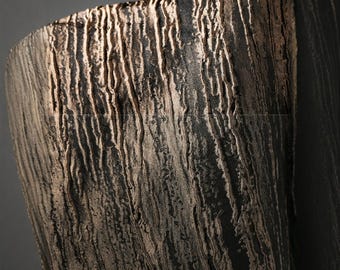 Puede incluir: Primer plano de una superficie texturizada de color marrón oscuro con patrones verticales y acanalados. La superficie tiene una apariencia rugosa y orgánica, con reflejos marrones más claros. El efecto general recuerda a la madera envejecida o la corteza.