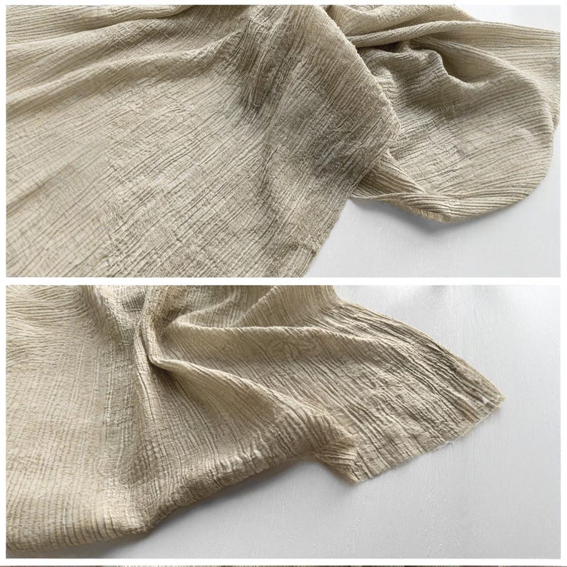 May include: Close-up of a beige fabric with a textured, crinkled appearance. The fabric is draped and folded, showcasing the detailed weave and subtle variations in colour. The material appears soft and lightweight, suitable for clothing or home decor.