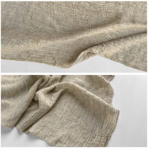 Puede incluir: Primer plano de una tela texturizada en un color beige neutro. La tela tiene un aspecto arrugado con l&iacute;neas verticales y horizontales, creando un efecto tejido. Los pliegues y el drapeado de la tela son visibles.