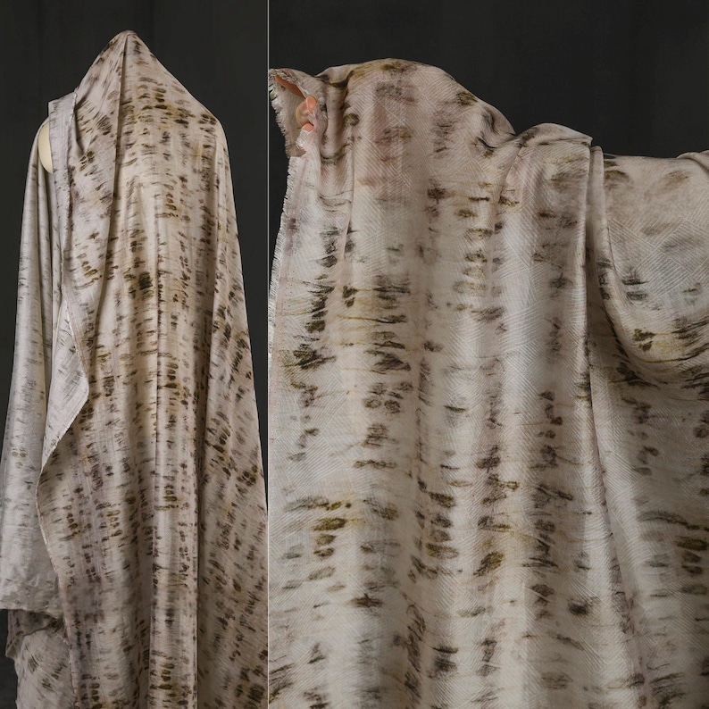 Puede incluir: Un textil drapeado con una base color crema y un patr&oacute;n de vetas verticales de color marr&oacute;n oscuro. La tela es suave y fluida, con una textura sutil. El efecto general recuerda a la veta de la madera natural o la corteza.