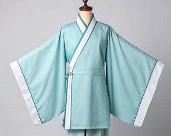 Könnte beinhalten: Ein hellblaues traditionelles Gewand im asiatischen Stil mit weiten Ärmeln und Wickeldesign. Das Gewand hat weiße Verzierungen und einen passenden Gürtel. Das Outfit wird auf einer Schaufensterpuppe präsentiert.