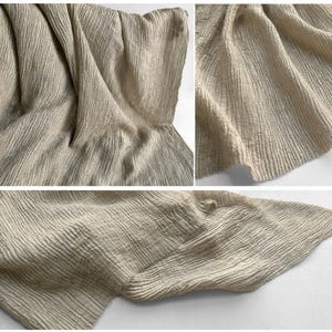 Puede incluir: Primer plano de una tela beige con una superficie texturizada y acanalada. La tela est&aacute; drapeada y doblada, creando sombras y reflejos que enfatizan la textura. El material parece suave y ligero, adecuado para ropa o decoraci&oacute;n del hogar.