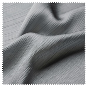 Può includere: Primo piano di un tessuto grigio con una trama a coste. Il tessuto è drappeggiato, mostrando pieghe e linee diagonali. Il materiale ha una lucentezza sottile, che suggerisce un tessuto liscio, possibilmente sintetico.