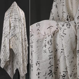Könnte beinhalten: Ein drapiertes, cremefarbenes Gewebe mit einem Muster aus schwarzer und grauer Kalligraphie. Der Stoff ist leicht und scheint fließend. Die Kalligraphie ist im traditionellen ostasiatischen Stil gehalten und bedeckt die gesamte Oberfläche.