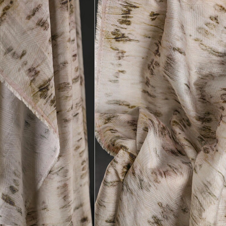 Puede incluir: Primer plano de una tela color crema con un patr&oacute;n texturizado. La tela presenta un dise&ntilde;o de pinceladas marrones y verde oliva, creando un aspecto natural y art&iacute;stico. Los bordes de la tela est&aacute;n deshilachados, lo que a&ntilde;ade encanto r&uacute;stico.