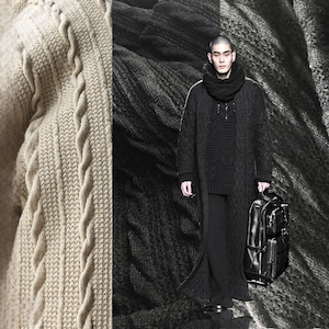 Könnte beinhalten: Ein Model in einem schwarzen Strick-Ensemble, einschließlich eines langen Cardigans, Schals und einer Hose, hält einen schwarzen Lederrucksack. Das Bild zeigt auch eine Nahaufnahme eines beigefarbenen Zopfstrickpullovers.